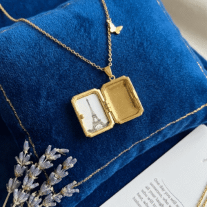 A vintage gold open book locket necklace displayed beautifully over a royal blue velvet cushion.