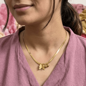 A delicate gold plated snake chain necklace featuring a textured butterfly pendant with dangling gold beads.