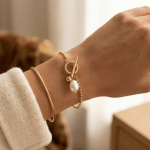 A beautiful Pakistani actress showcasing a layered gold bead chain bracelet with a freshwater pearl toggle clasp.