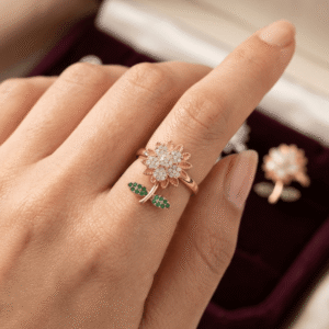 A beautiful manicured hand of a female model styling a rose gold sunflower crystal stem ring with green leaf rhinestones on her finger.