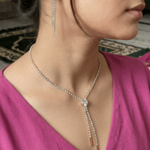 A beautiful Pakistani actress with a subtle smile styling a gold rhinestone Y-shaped lariat necklace around her neck.