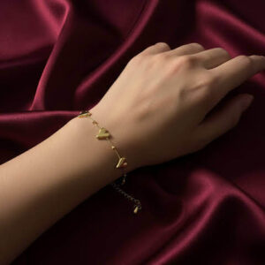 A premium gold multi heart chain bracelet with multiple polished heart charms displayed on a woman's wrist against a luxury maroon satin silk background.