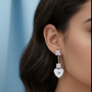 A model wearing premium silver heart drop earrings with white enamel charms and square crystals against a light blue background.
