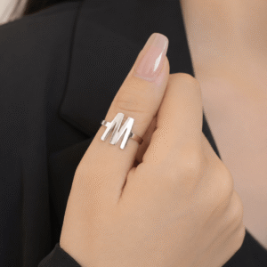 Woman wearing a silver letter M initial ring with a sleek minimalist personalized design on her finger.