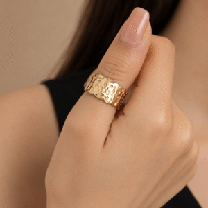 Woman wearing a gold hammered texture statement ring with a modern wide band design on her finger.