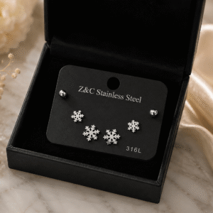 Snowflake Spark Stud Earrings in polished 316L stainless steel displayed inside a luxury black jewelry gift box on a marble surface.