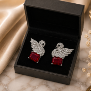 Elegant silver swan stud earrings featuring sparkling crystals and ruby-red gemstone accents.